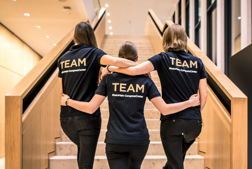 Drei Frauen in schwarzen T-Shirts mit dem Wort Team auf dem Rücken