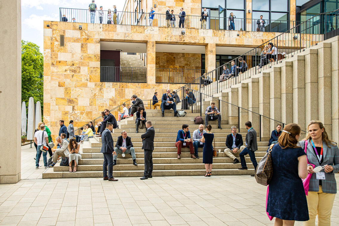Kongressgäste verbringen ihre Pause an den Treppen vor dem RMCC