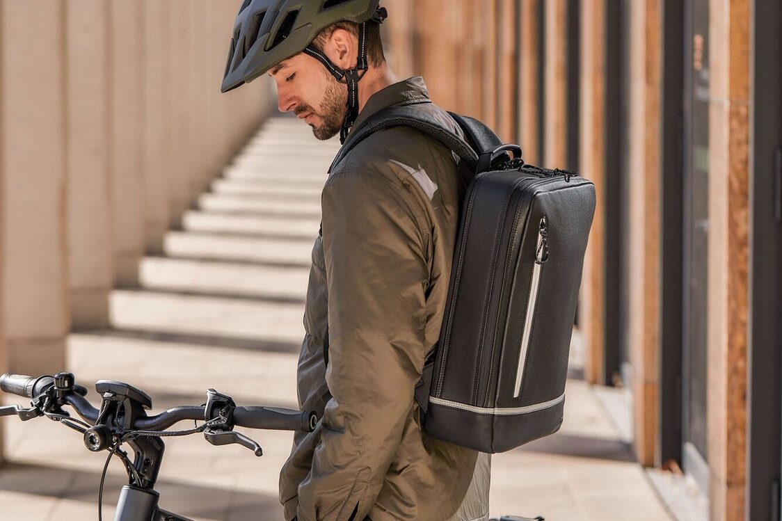 Ein Mann steht mit dem Rucksack und mit dem Fahrrad