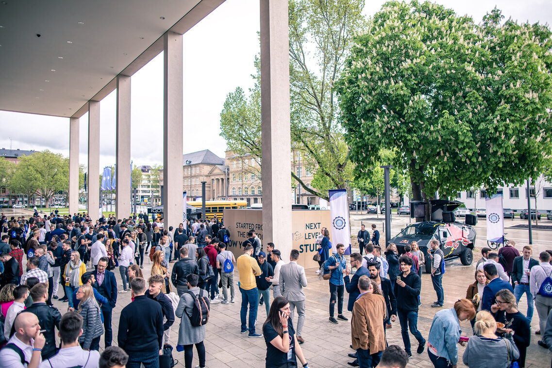 Menschen stehen vor dem Haupteingang ins RMCC