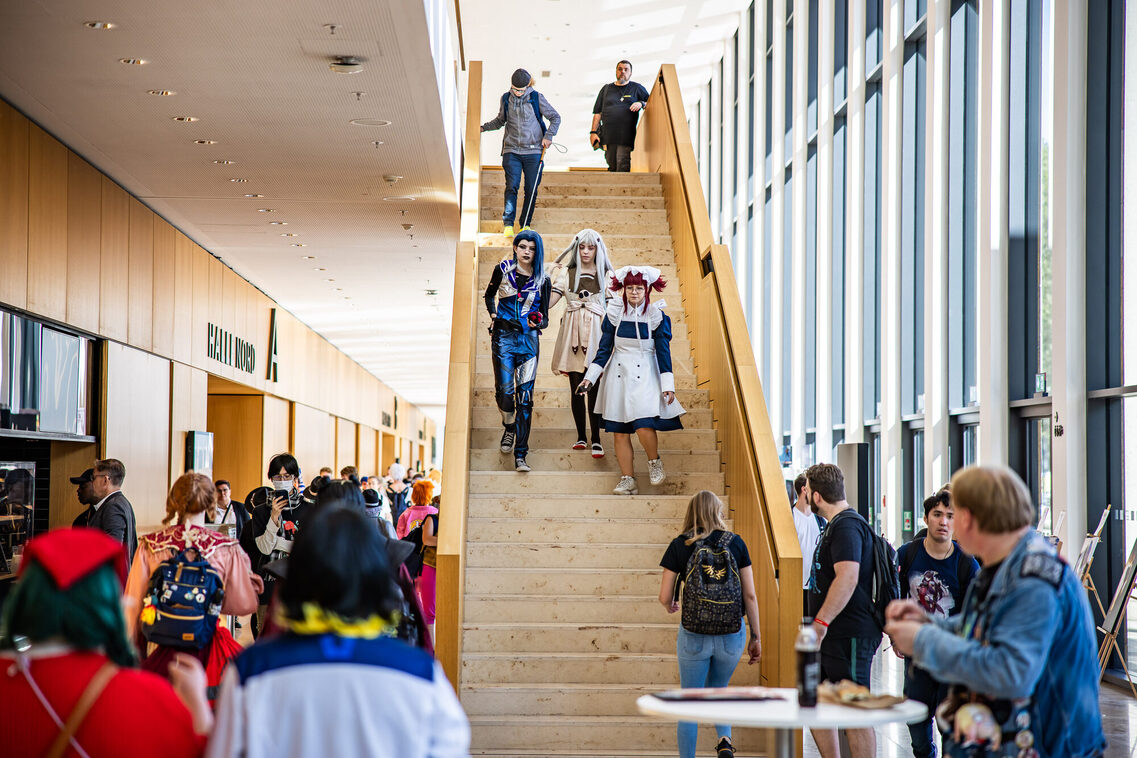 Drei Menschen in Manga-Kostümen gehen die Treppe runter