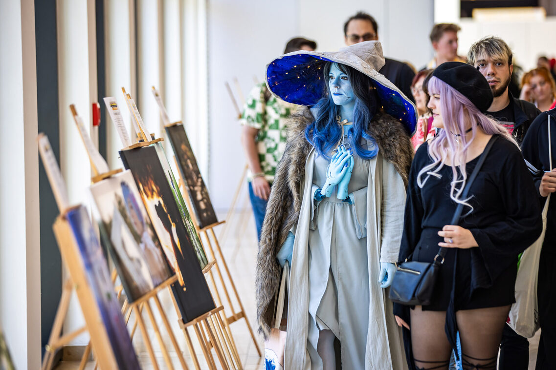 Zwei Frauen in Manga-Kostümen schauen sich die Bilder an.