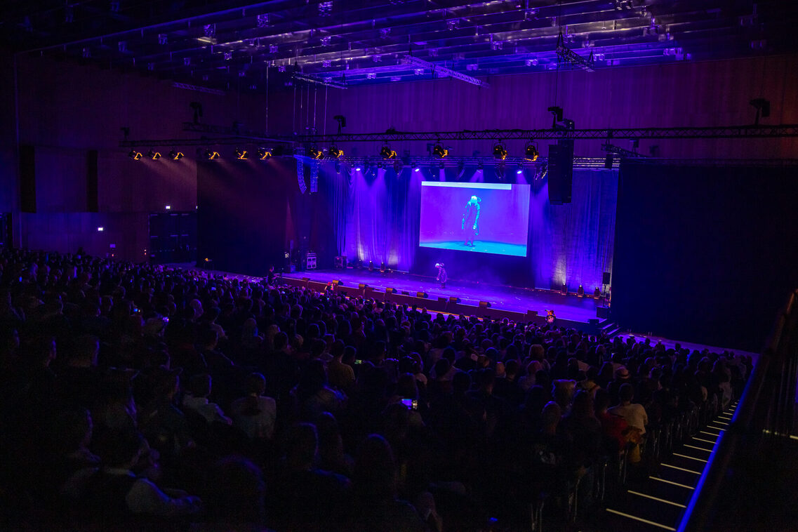Veranstaltungsgäste auf der Tribühne in der Halle Nord