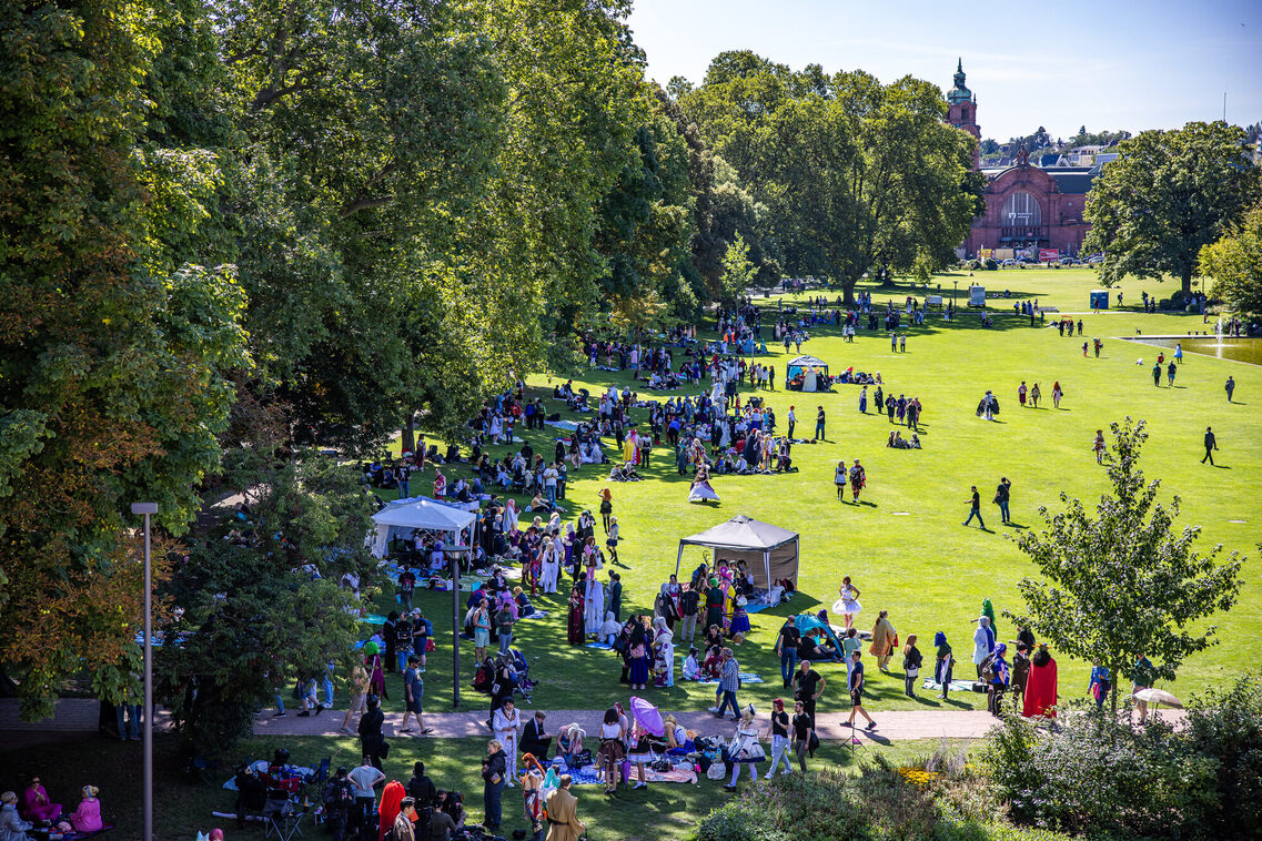 Veranstaltungsgäste sitzen auf der Wiese in den Reisinger Anlagen vor dem RMCC