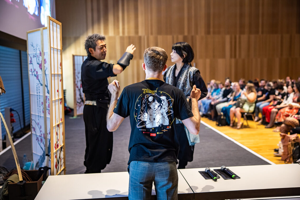 Gäste sitzen in der Reihenbestuhlung und hören den Vortrag zu