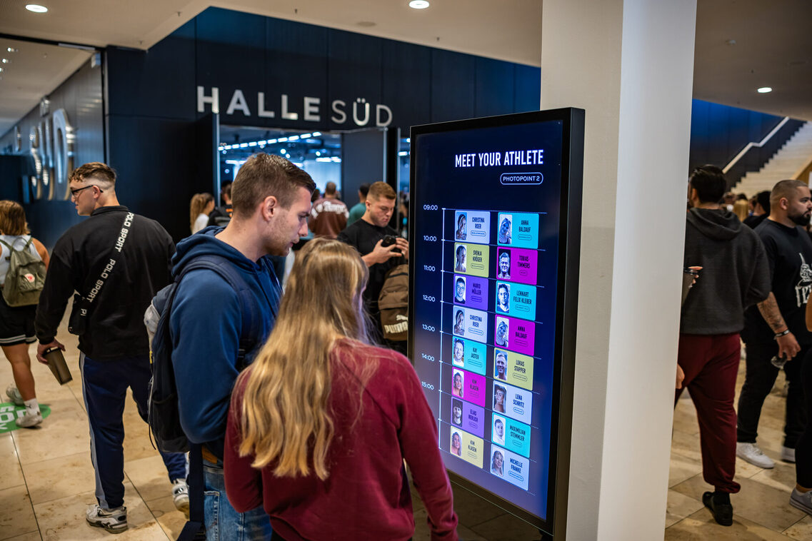 Ein MAnn und eine Frau stehen vor dem Wegeleitsystem im RMCC