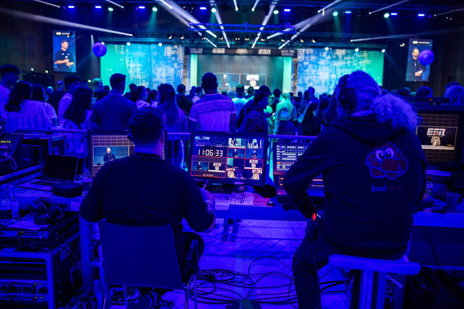 İki adam bir etkinlik sırasında ekranların arkasında oturuyor ve bir film yönetiyor.