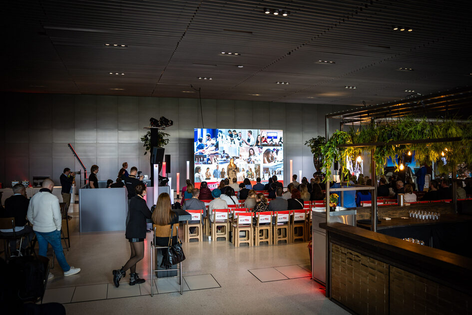 İnsanlar sergi salonundaki sahnenin önünde oturuyor