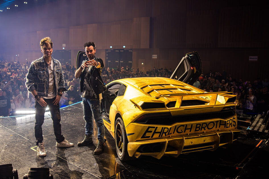 Ehrlich Kardeşler sarı bir araba ile sahnede