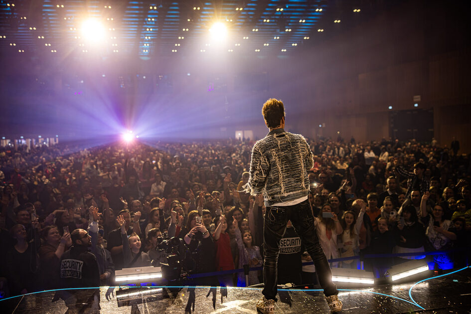 Bir adam sahnede seyircilerin önünde duruyor