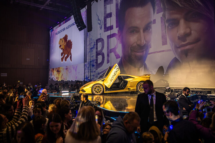 Ein gelbes Auto steht auf der Bühne vor dem Publikum