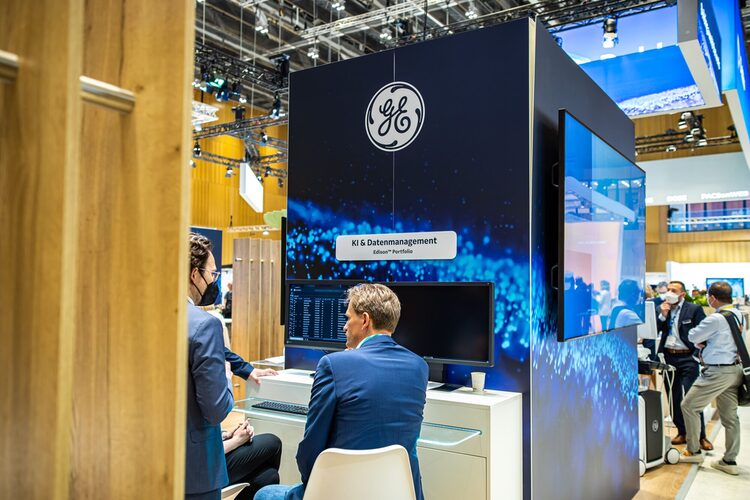 Zwei Kongressgäste sitzen und unterhalten sich am Messestand